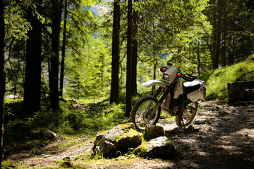 Fototapeta na wymiar Mountain motorcycle standing on a cycling trail in the forest of alps mountains