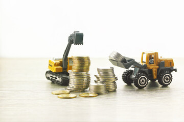 Pile of coins and heavy duty vehicle construction in investment and financial saving concept..