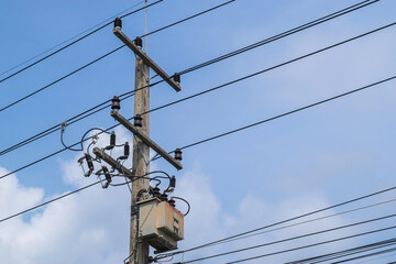 Transformers on cement high voltage pole and electric wire with fuse and white cloud with blue sky.