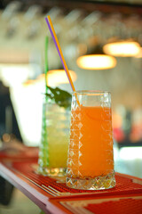 Cold summer alcohol cocktail with ice and fruit in a tall glass on light blurred restaurant or cafe background.