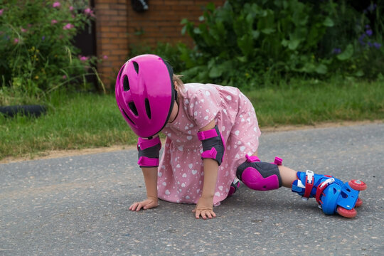 A little girl roller skating in full protection fell on the asphalt