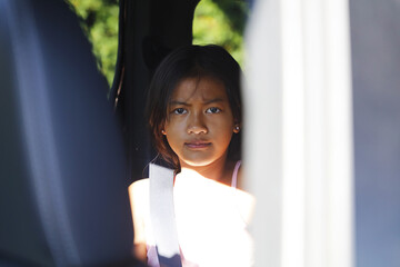 A cute asian girl is irritated in the back of a car