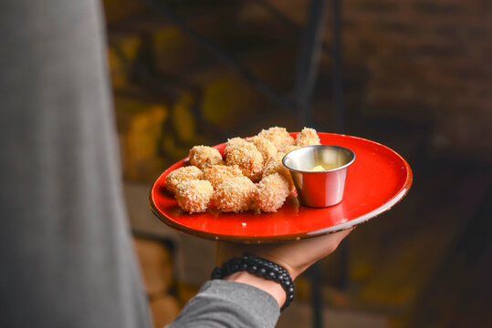 Mixed deep fried appetizer with chili sauce and mustard dip. Deep fried snacks for beer. Served on a red plate.