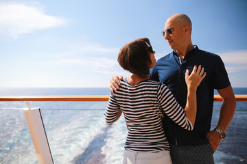 caucasian man and brunette woman in sunglasses traveling together on cruise ship,standing on balcony and enjoying with beautiful view of Caribbean sea