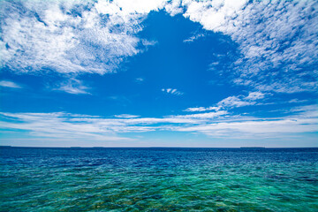 Naklejka na ściany i meble Turquoise sea with coral and circular cloud in the blue sky in a sunny day