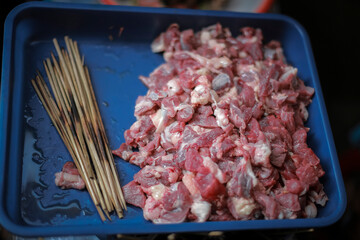 Satay goat (Sate kambing) satay lamb, lamb or meat goat satay in grilling place with smoke by people with yummy looking. traditional satay from java, Indonesia. Close Up Macro