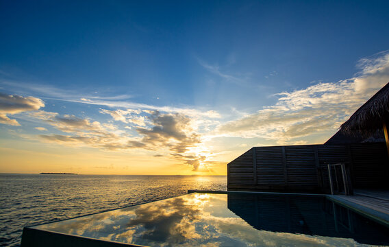 Sunset viewed from a water bungalow with private pool and mirror reflection of the sky from the pool water