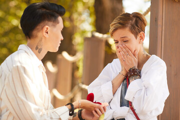 Woman proposing to her happy girlfriend outdoors love and marriage concept