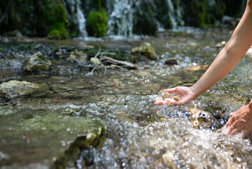 Female hands holding little stones and water from the clear mountain river.