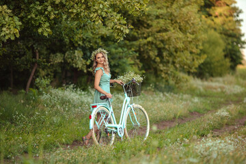 Fototapeta premium girl in a dress with a bouquet of daisies walking in the woods with a vintage bike
