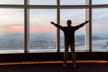 Female tourist enjoying view of Seoul from tower at sunset