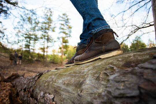 Man in leather boots standing on the tree trunk - close up photo with selective focus