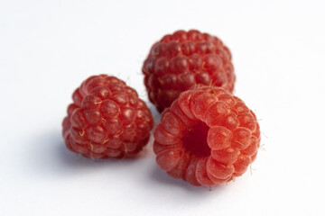 Three ripe raspberries isolated on a white background close-up. Fresh raspberries without sheets on the table. Macro shooting. Healthy and wholesome food concept