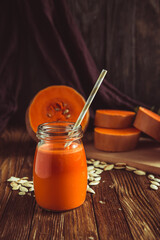 glass of pumpkin juice placed on table near the pumpkins