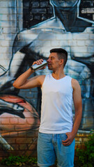 Young athlete in white t-shirt with soda can on graffiti background