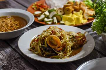 Spicy thai green papaya salad or thai name Som Tum (a famous local Thai street food) with Nam Neung (Vietnamese Meatball Wraps) background