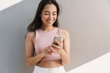 Image of joyful asian beautiful girl using mobile phone