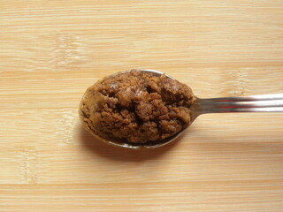 Brown color Sugarcane jaggery granules on stainless steel spoon