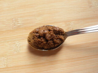 Brown color Sugarcane jaggery granules on stainless steel spoon
