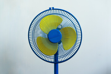 A colorful blue and yellow standing fan - obrazy, fototapety, plakaty
