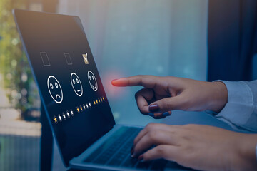 Businesswoman pressing face emoticon on the conputer laptop screen. Customer service evaluation and...