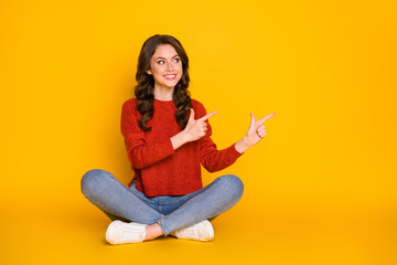 Photo of attractive funny lady sit floor legs crossed direct fingers side empty space showing novelty product wear casual outfit isolated bright yellow color background