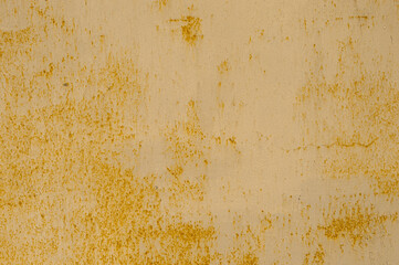 Texture of rusty corrosive metal fence, with flattened yellow paint from dilapidation. Rusty non ferrous metal. Cracks of yellow paint from weathering on the surface of the metal sheet..