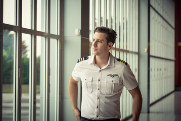 Confident pilot. Confident male pilot in uniform with airplane in the background