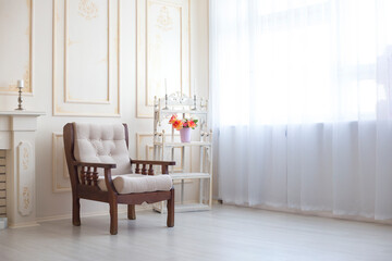 Wooden armchair stands in the white room next to the window. Vintage furniture. Interior of a room with a window