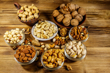Assortment of nuts on wooden table. Almond, hazelnut, pistachio, peanut, walnut and cashew in small bowls. Healthy eating concept