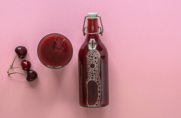 Summer cherry juice in a glass and bottle with ripe berries