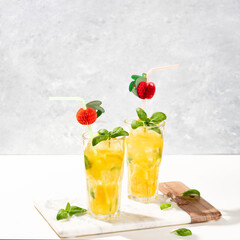 Citrus lemonade or mojito cocktail with lemon and orange and basil. Cold beverage or drink with ice on marble cutting board