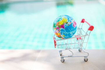 Earth global in shopping cart over blurred blue water background, outdoor day light, online shopping © sirirak