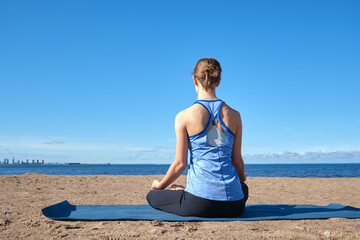 Young slender girl doing yoga on the beach on a sunny morning, sad mood, sad thoughts