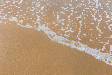 Fototapeta na wymiar Sandy beach with waves. Empty sea and beach background with copy space