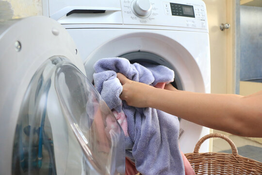 Woman hands loading linen into wahing machine - closeup shot,Loading laundry in the washing machine. a hand opens the door of the washer. Dirty clothes are inside the washing