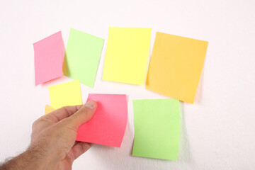 male hand put a balnk paper sticky note on the wall with copy space for your text