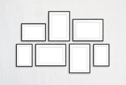 Photo frames set isolated on white textured wall, seven blank realistic frameworks, interior decor mock up