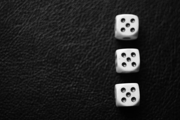 Three dice with fives on a black leather table. Bw photo. Top view.