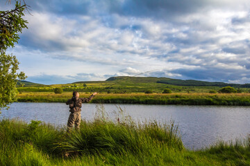 A fisherman fly fishing in the evening on the Blackwater of Dee, Scotland