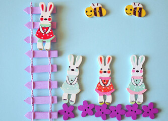 Easter greeting card with cute bunnies, wooden stairs, flowers, bees against light-blue background. Spring and summer composition.  Baby Happy Birthday card. DIY. Design ideas. 