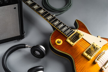 Selective focus of Guitarist's set concept, orange  electric guitar, headphone and accesories on grey background