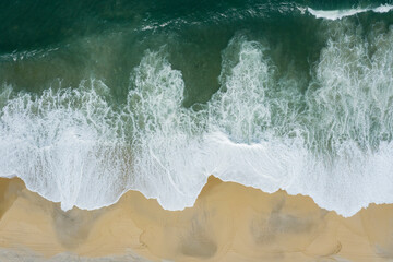 Wave and sand. Top view of a beach with bare footprints along.