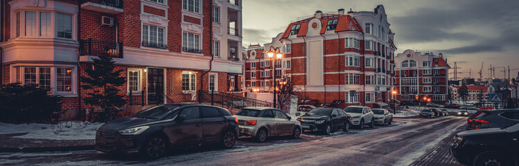 Fototapeta na wymiar Empty city street, parked cars and road in snow.