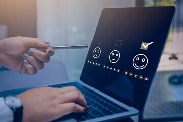 Businesswoman pressing face emoticon on the conputer laptop screen. Customer service evaluation and survey concept.