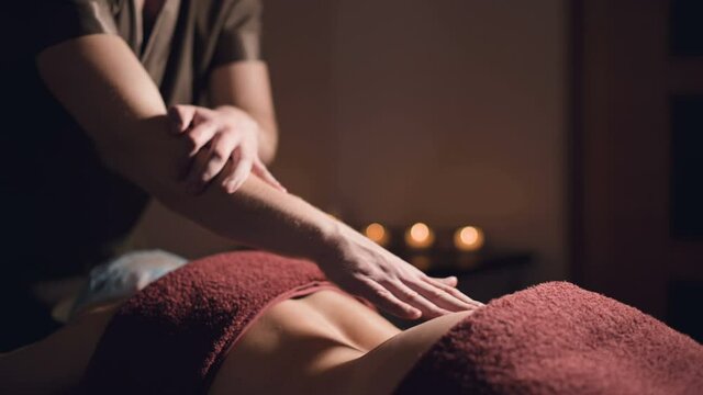 close-up Cosmetology and physiotherapy. Professional massage to the lower back of a woman is made by a masseur man. Concept of manul therapy and massage spa treatments