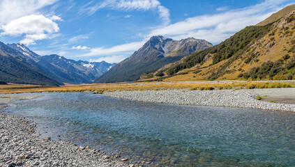 A shallow, fast flowing river, in the mountains of New Zealand on a sunny day