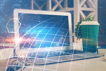 Double exposure of desktop with computer and world map hologram. International data network concept.