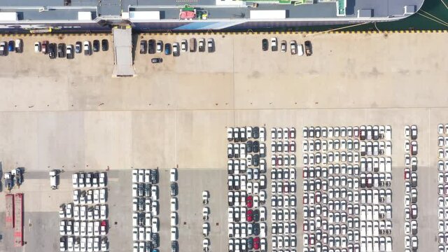 Cars export terminal in export and import business and logistics. Shipping cargo to harbor. Aerial view of a large number of new cars lined up outside an automobile factory ready to ship over sea.