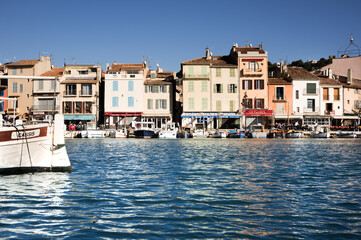 The tranquil harbor of ancient Cassis in France in sunlight, front view with boat.